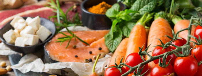 Käsewürfel in Schale, rohes Lachsfilet auf Papier mit Möhren, Tomaten und frischer Minze 